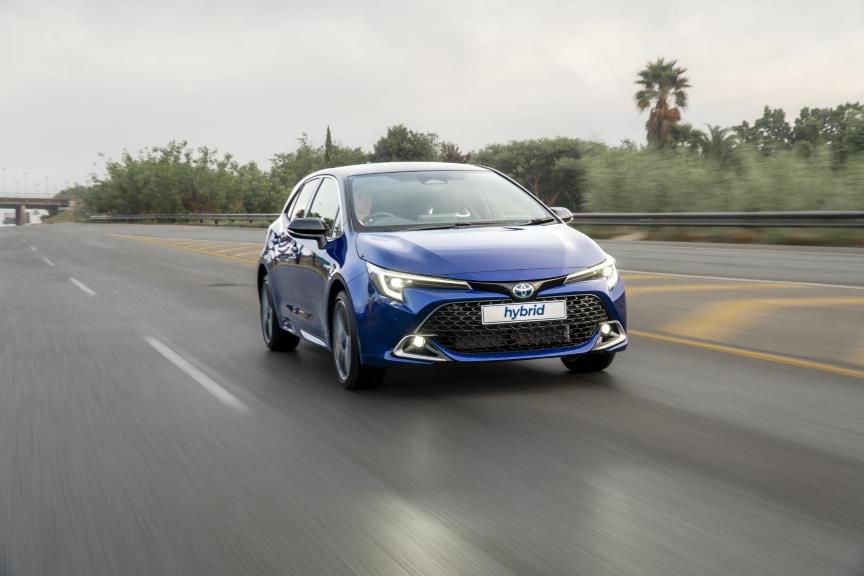 A blue Toyota Corolla sedan hybrid driving down the highway.