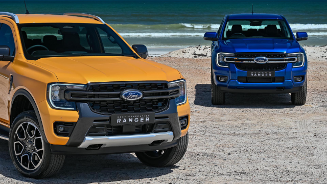 Blue and yellow Ford Ranger trucks parked on a sandy beach