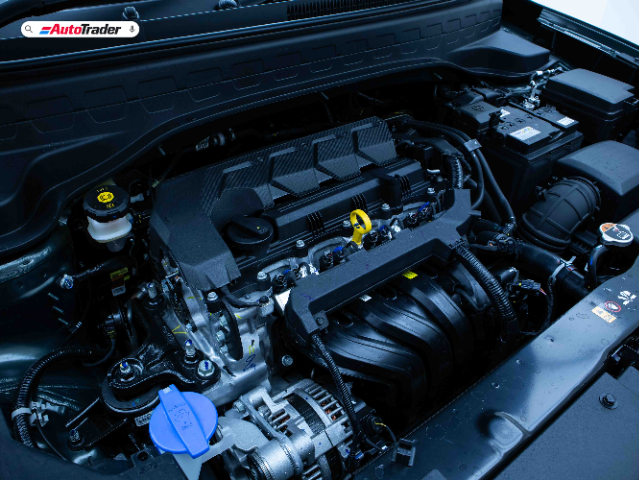 The image shows the engine bay of a Kia Sonet. The engine components are clearly visible, including the engine cover, various hoses, and fluid reservoirs. The AutoTrader logo is displayed in the top left corner of the image.