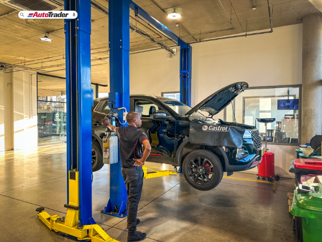 Technician lifting vehicle on two post lift