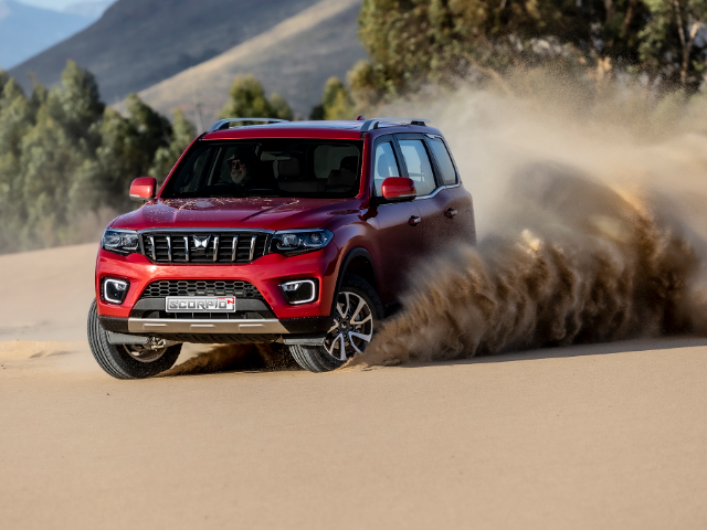 A red Mahindra Scorpio-N taking a turn on soft sand