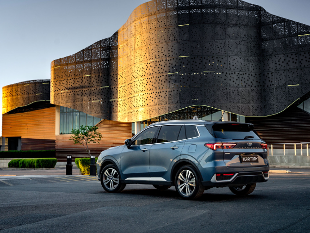 Rear three quarter view of a silver blue Ford Territory against a modern urban backdrop