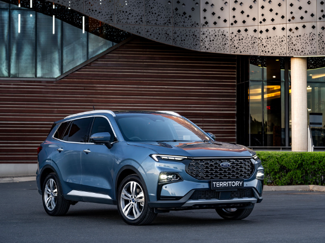 Front view of the blue Ford Territory Titanium SUV parked in front of a modern building