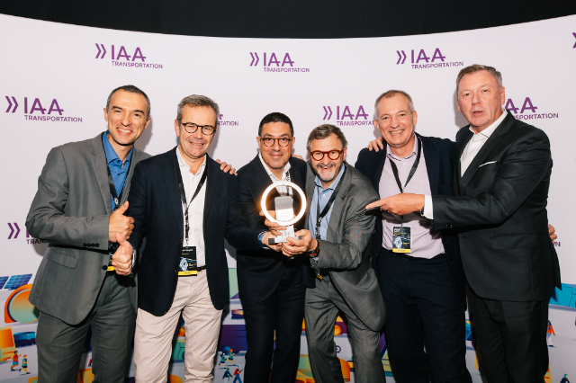 A group of six men are celebrating and posing with an award at the IAA Transportation event.