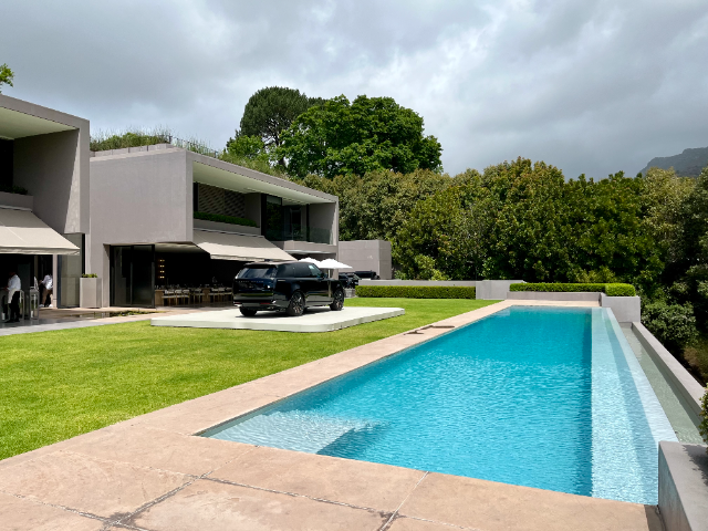 A long lap pool in front of an ultramodern, cubist-style house.