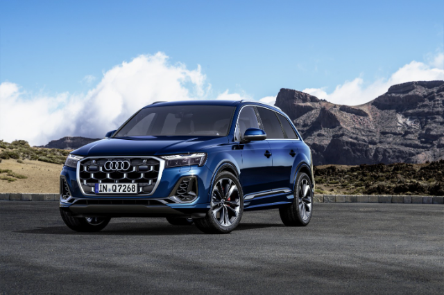 A blue Audi Q7 with mountains in the background.