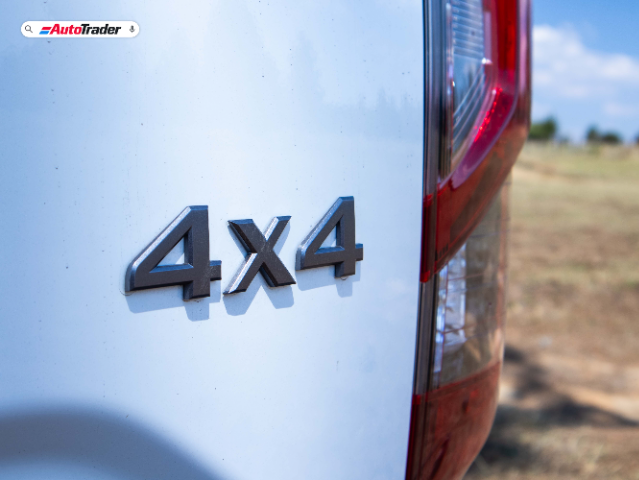 Close-up view of the rear side of a white Nissan Navara PRO-4X, focusing on the "4x4" badge. The image also shows part of the vehicle's taillight and a blurred outdoor background. The AutoTrader logo is visible in the top left corner.