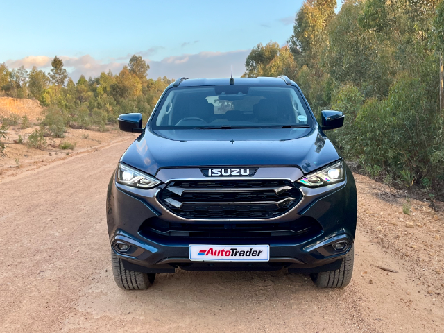 A Norwegian Blue mu-X on a dirt road with trees in the background.