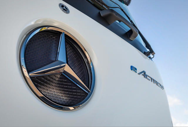 The image shows a close-up of a Mercedes-Benz logo on a vehicle with the word "Actros" visible on its side.