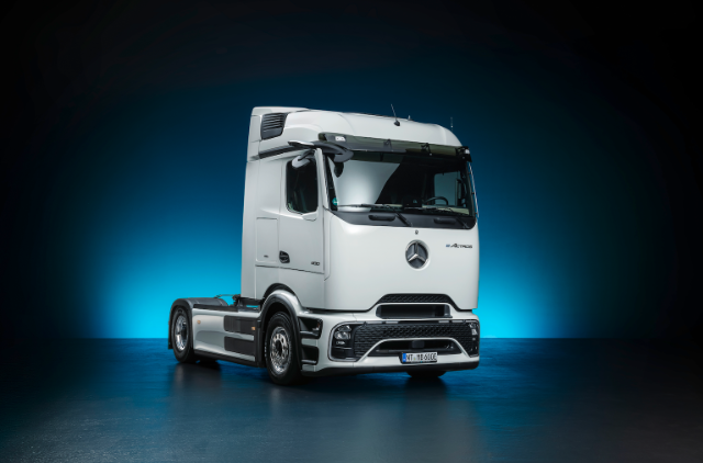 The image shows a sleek, modern white semi-truck with a prominent Mercedes-Benz logo, set against a gradient blue background.