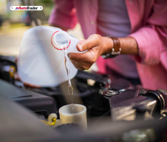 man refilling coolant on a car