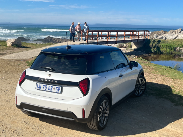 People looking at the MINI parked in front of a bridge.