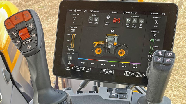 The image shows a close-up of a JCB Fastrac tractor's control system. In the foreground, there are two control handles with buttons, labeled with numbers and letters. The larger central display screen shows a digital interface with a tractor illustration, various control settings such as control profile, engine speed, transmission, and steer mode. 