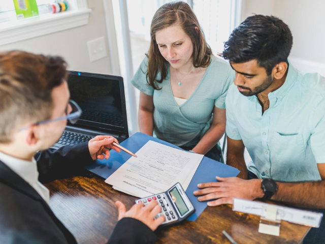 Man and woman discuss finances with an agent while seated at a desk