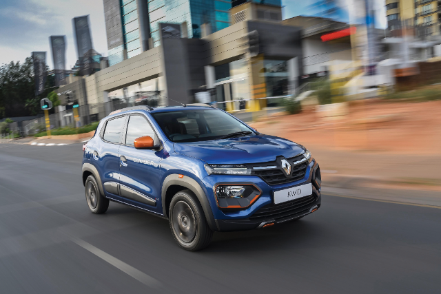 A blue Renault Kwid driving through town.