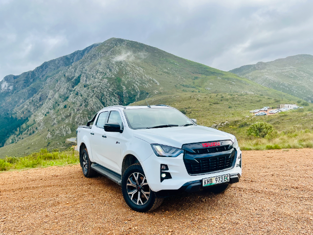 A white Isuzu X-Rider on a dirt road.
