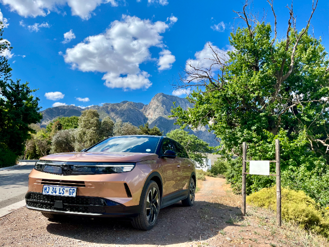The Grandland with mountains behind it under a blue sky.