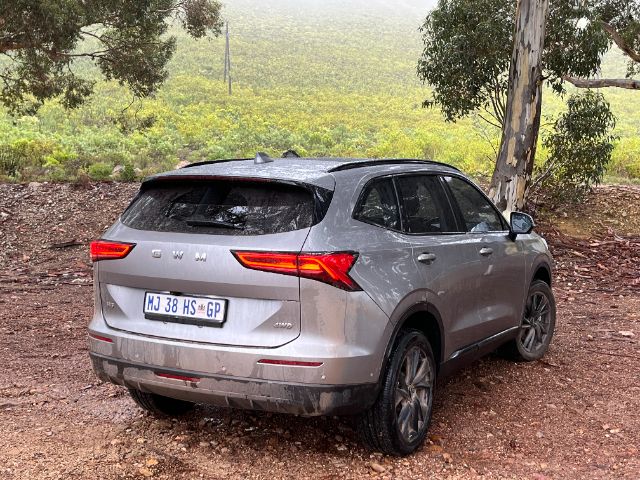 Three-quarter rear view of the H6 with a green hill in the background.