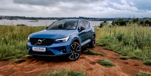The Volvo XC40 parked next to a river on bright brown dirt.