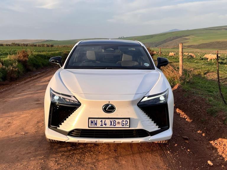 Full frontal view of the sharply styled lexus RZ bathed in golden light on a farm road.