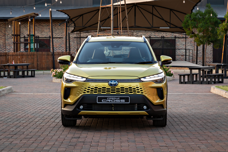 A golden Toyota Corolla Cross  parked in an urban setting.