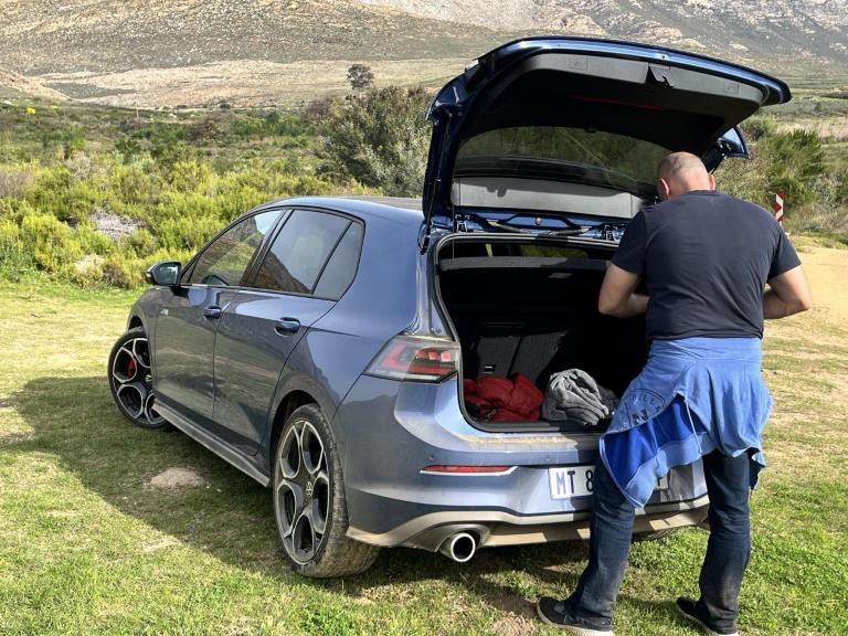 The GTI with an open boot with a man standing behind it.