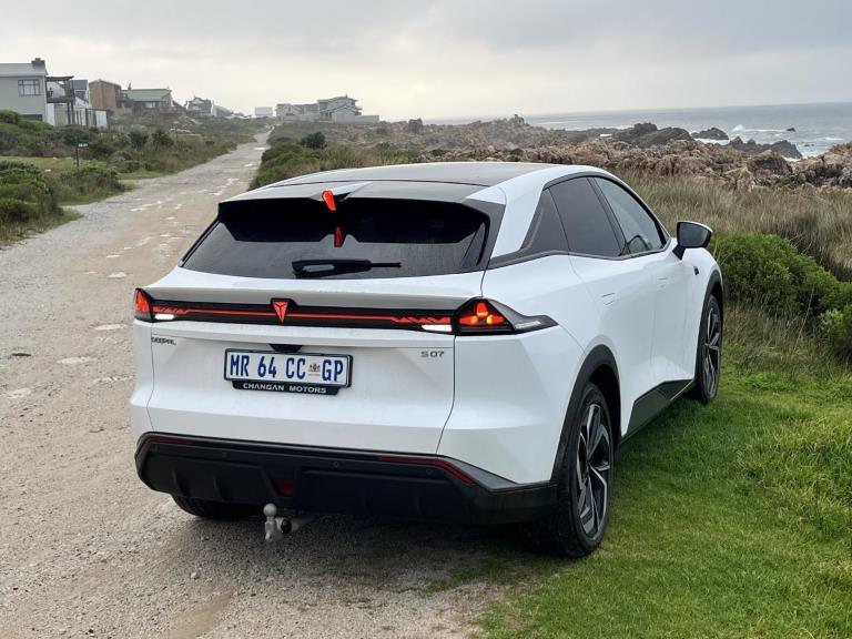 Rear three-quarter view of the 2026 Deepal S07 at sunset near the coast, parked on green grass.